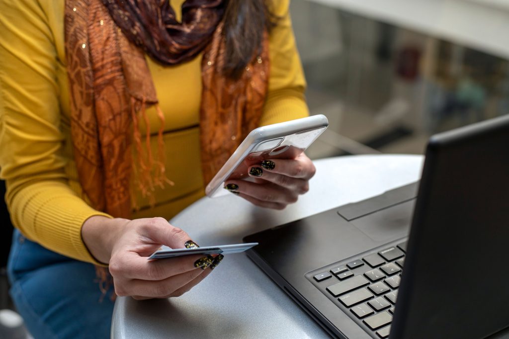 Closeup of a Hispanic female holding her smartphone and credit card to make an online payment