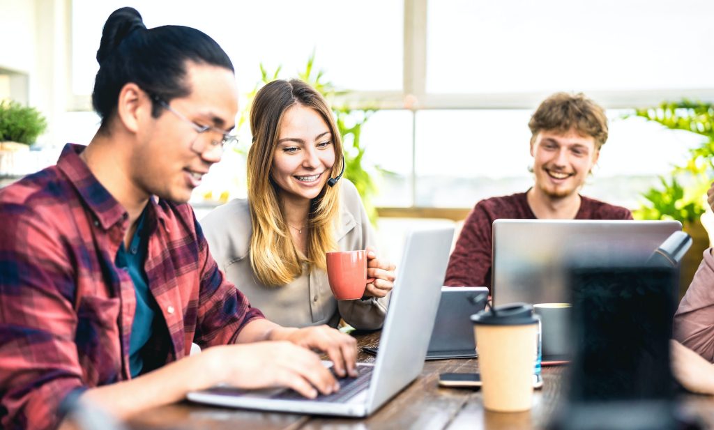 Young employee coworkers sharing content on laptop at startup studio